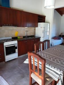 a kitchen with a table and a stove and a refrigerator at Cabaña Azul in Villa Anizacate +7 photos