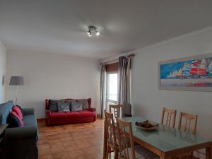 ein Wohnzimmer mit einem Tisch und einem roten Sofa in der Unterkunft Alltravel Atlântico apartment in Portimão