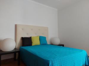 1 Schlafzimmer mit einem blauen Bett und 2 Tischen in der Unterkunft Alltravel Atlântico apartment in Portimão