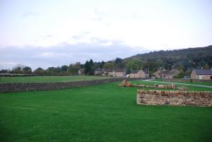a field of grass with a stone wall and sheep at Kingfisher Lodge in Froggatt