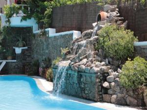 a swimming pool with a waterfall in a yard at Mykonian Iros Suites & Villas in Kalo Livadi
