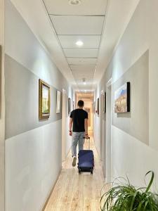 a man walking down a hallway with a suitcase at Cicerone Guest House in Florence