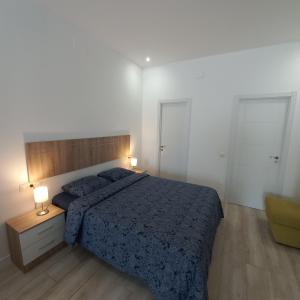 sypialnia z łóżkiem z niebieskim kocem i 2 lampami w obiekcie Apartamento VELARDE CENTER one w Maladze