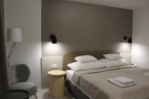 a bedroom with a bed with white pillows and a chair at Szkíta Panzió in Balatonmáriafürdő +7 photos