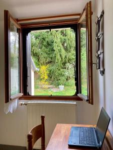 laptopa siedzącego na stole przed oknem w obiekcie Logisfontainebleau w mieście Villiers-sous-Grez