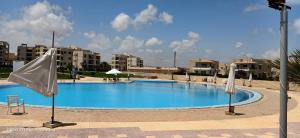 a large blue swimming pool with a white flag at Le Beau Site Chalet in El Alamein