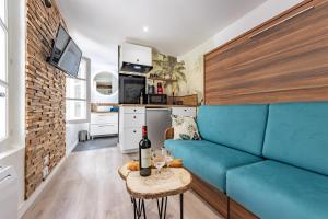 a living room with a blue couch and a table at Chez Ingres - Le Nid - Joyau caché en centre ville in Montauban