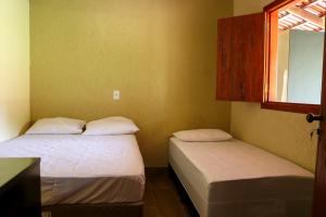 twee eenpersoonsbedden in een kamer met een raam bij CHACARA ESPERANÇA in Pirenópolis