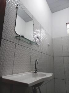 uma casa de banho branca com um lavatório e um espelho em POUSADA DO BETO em Atins