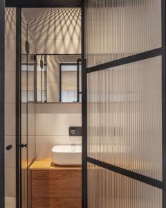a bathroom with a sink and a glass door at DeBlox living - Ben Avigdor Apartments in Tel Aviv