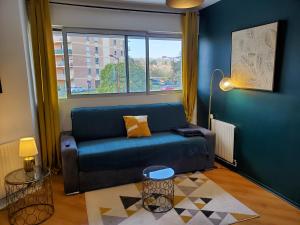 uma sala de estar com um sofá azul e uma janela em CHARMANT STUDIO☆NETFLIX☆CANAL+☆CANAL SAT☆PARKING☆ em Ramonville-Saint-Agne