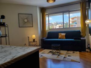 un soggiorno con divano blu e una grande finestra di CHARMANT STUDIO☆NETFLIX☆CANAL+☆CANAL SAT☆PARKING☆ a Ramonville-Saint-Agne