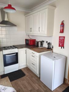 La cuisine est équipée de placards blancs et d'un four avec plaques de cuisson. dans l'établissement Miriam's Cottage West Cork, à Drom dhá Liag