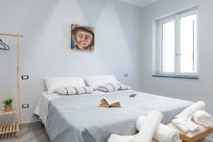 a white bedroom with a bed with a book on it at Albergo Libera Gioventù in Torre Annunziata
