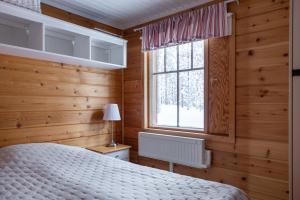 um quarto com paredes de madeira, uma cama e uma janela em Pyhä Saukonpiilo em Pelkosenniemi