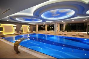 a large swimming pool in a building with a ceiling at Konak Tower Seaside in Alanya