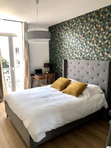 a bedroom with a large bed with white sheets and gold pillows at Sainte Cécile 5 - T3 élégant, limineux et central in Vichy