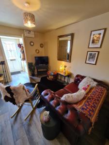 a living room with a leather couch and a table at The Shambles by Spires Accommodation A Boho styled place to stay just 3 miles from Birches Valley visitors Centre Cannock Chase in Rugeley