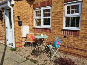 a table and two chairs in front of a brick house at The Shambles by Spires Accommodation A Boho styled place to stay just 3 miles from Birches Valley visitors Centre Cannock Chase in Rugeley