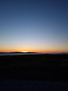 a sunset in the middle of a field at Abhaig Boutique B&B - Small & luxurious in a great location! in Uig