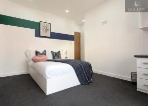 a bedroom with a white bed with a green stripe on the wall at Leicester's Lyter living Serviced apartments Opposite Leicester Railway Station in Leicester
