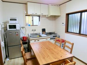 eine Küche mit einem Holztisch und einem Kühlschrank in der Unterkunft Sepia Court Inn セピアコートイン in Urayasu