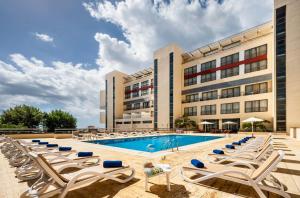 uma piscina do hotel com espreguiçadeiras e um edifício em Sao Miguel Park Hotel em Ponta Delgada