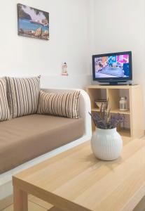 un salon avec un canapé, une table et une télévision dans l'établissement George's Place Sifnos - apartments, à Apollonia