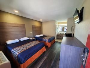 a hotel room with two beds and a flat screen tv at River Inn Motel in San Antonio