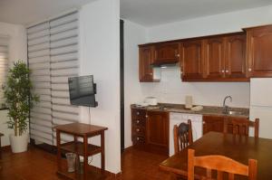 cocina con armarios de madera, mesa y TV en Holiday House Always Sun, en Playa de Santiago