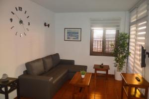 a living room with a couch and a clock on the wall at Holiday House Always Sun in Playa de Santiago