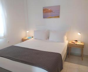 une chambre avec un grand lit blanc avec deux tables de nuit dans l'établissement George's Place Sifnos - apartments, à Apollonia
