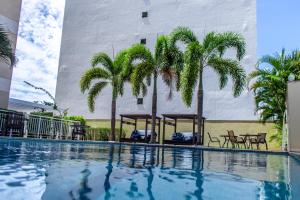 ein Schwimmbad vor einem Gebäude mit Palmen in der Unterkunft Delmond Hotel in Cuiabá