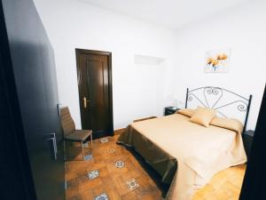 ein Schlafzimmer mit einem Bett und einem Stuhl darin in der Unterkunft Alojamiento Los Alcornocales in Medina-Sidonia