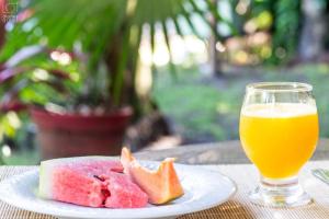 um prato de melancia e um copo de sumo de laranja em Baía Sul Hotel em Barra Grande