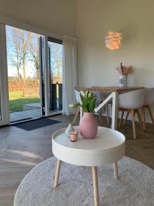 una sala de estar con una mesa y un jarrón en un taburete en Buitenlede 7 - Suite M, en Dwingeloo