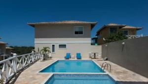 a swimming pool in front of a house at Casa em condomínio com piscina na Praia Rasa in Búzios