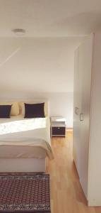 a white bedroom with a bed and a night stand at VISOKO Room in Visoko