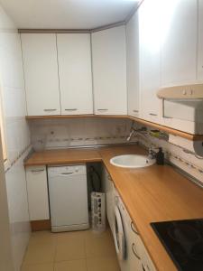 eine kleine Küche mit weißen Schränken und einem Waschbecken in der Unterkunft Apartamento céntrico in Madrid