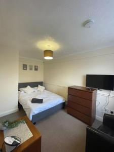 Habitación con cama, escritorio y TV. en 6 Bedroom House For Corporate Stays in Corby Suitable for Nightshift Workers, en Great Oakley