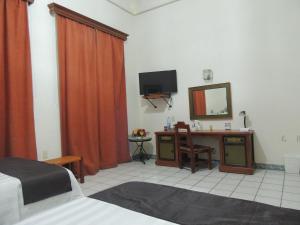a bedroom with a bed and a desk with a mirror at Hotel Concierge Plaza Colima in Colima