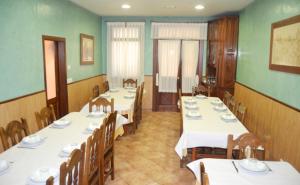 a dining room with white tables and wooden chairs at Pensión Carballeira in Arzúa