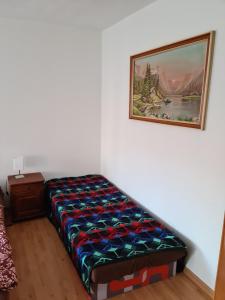 a bed in a room with a painting on the wall at Penzión Larix Blatnica in Blatnica