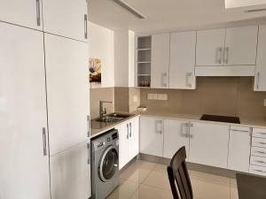a kitchen with white cabinets and a washing machine at iTowers luxurious 1-Bedroom apartment- 15th Floor in Gaborone