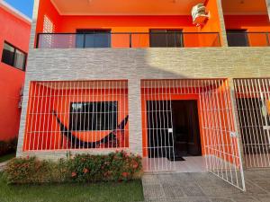 an orange building with a gate in front of it at Casa Lua Cheia na Praia de Peroba, Maragogi in Maragogi