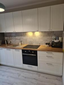 a kitchen with white cabinets and a stove top oven at Pod Świerkami in Myślibórz