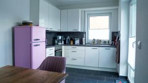 una cucina con frigorifero rosa e tavolo di Haus Nordseeliebe mit Außensauna, Outdoor Dusche und Wallbox a Dornum