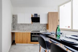 eine Küche mit einem Tisch mit Stühlen und einer Flasche Wein in der Unterkunft Perfect Location, Modern 2BR Apartment in Sliema
