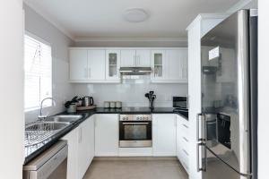 uma cozinha com armários brancos e um frigorífico de aço inoxidável em Kingswood Manor No.17 em George