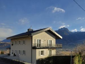 a house with a balcony and mountains in the background at La Vista - Apartment mit Traumblick & Garten in Marlengo